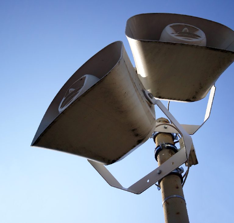 Outdoor speakers against a clear blue sky.