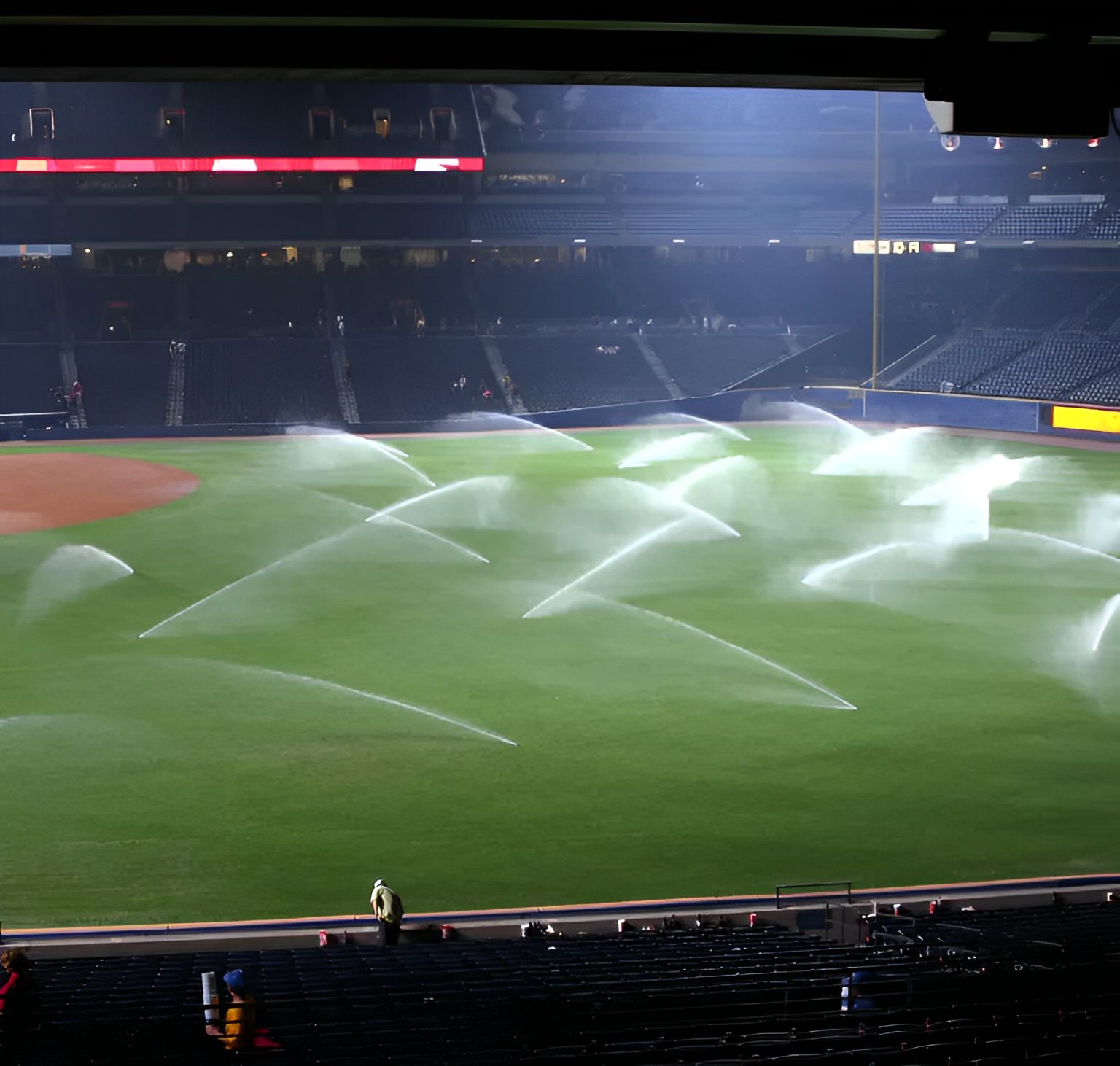 Baseball field being watered at night.