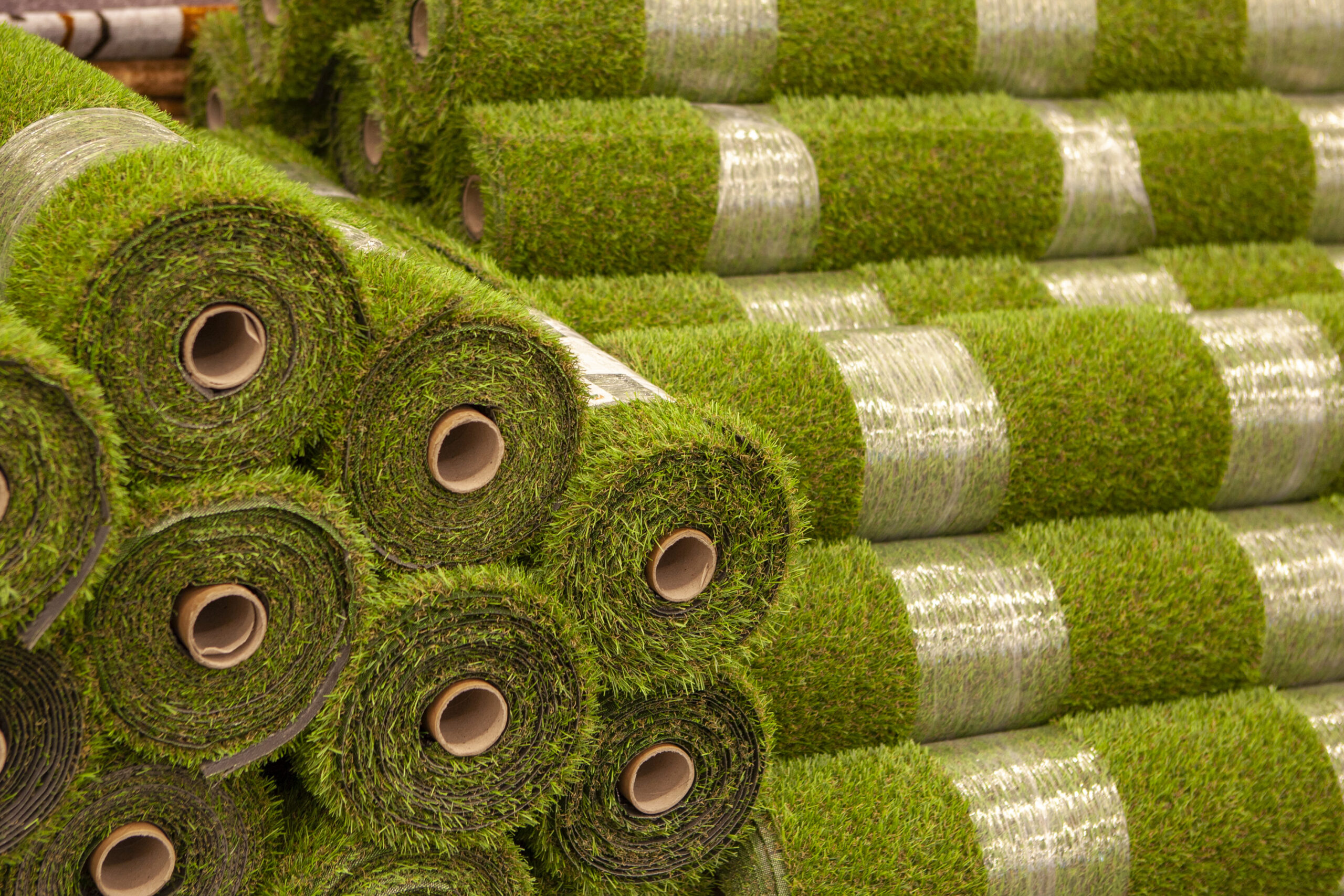 A pile of rolls of green grass next to each other.