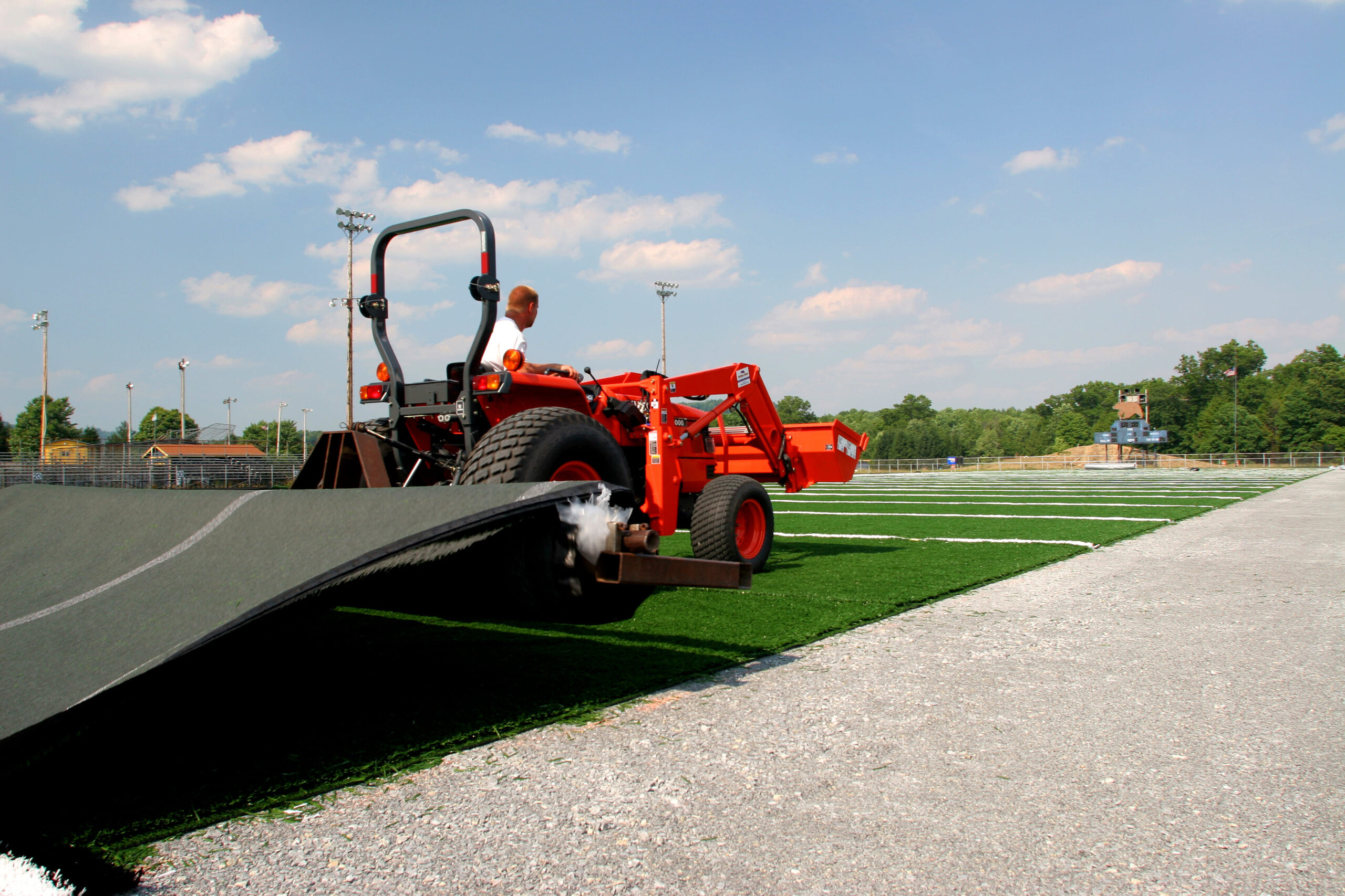 A tractor is parked on the grass near a field.